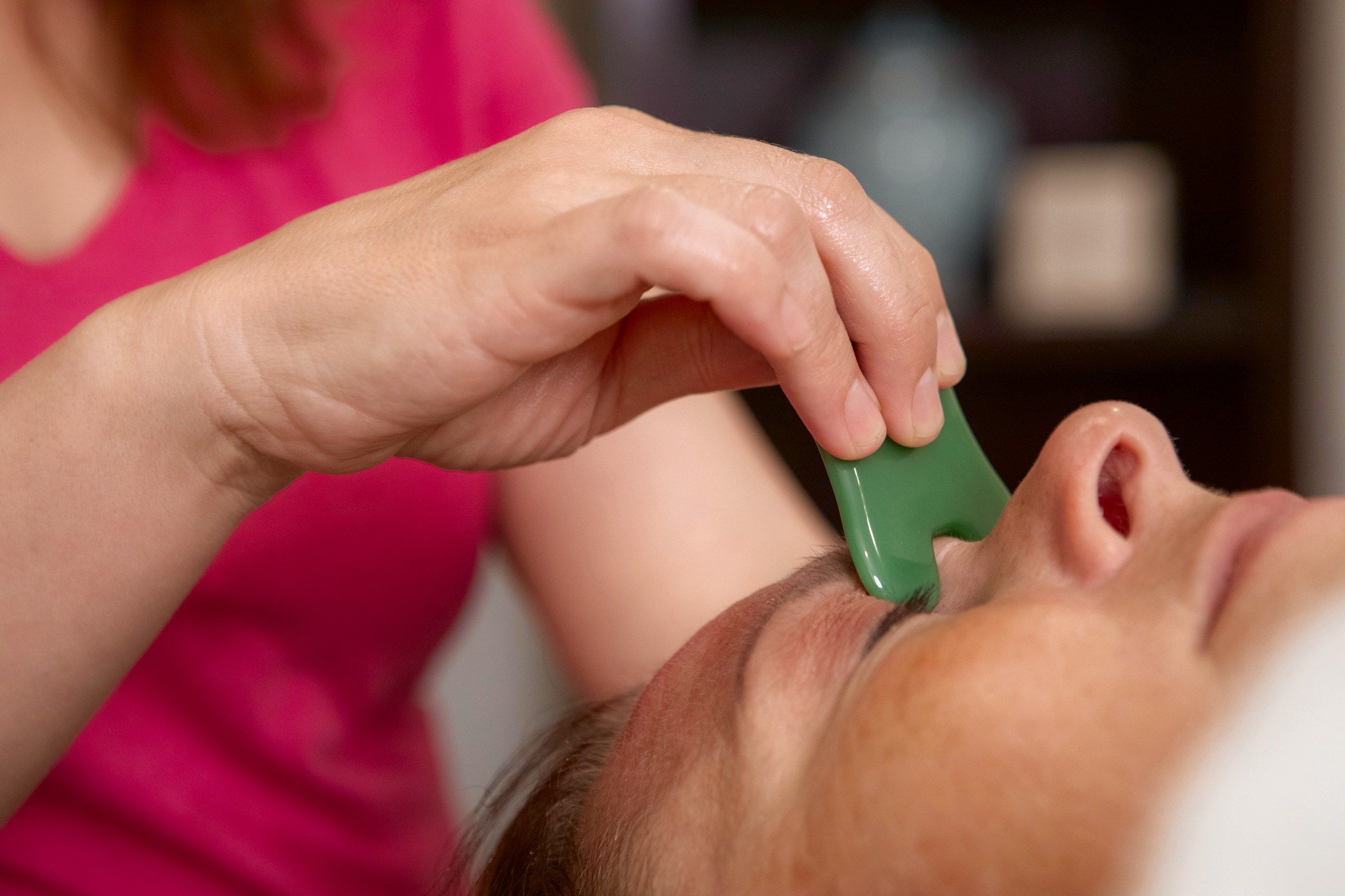 Krissy drawing a gua sha stone along a client's brow