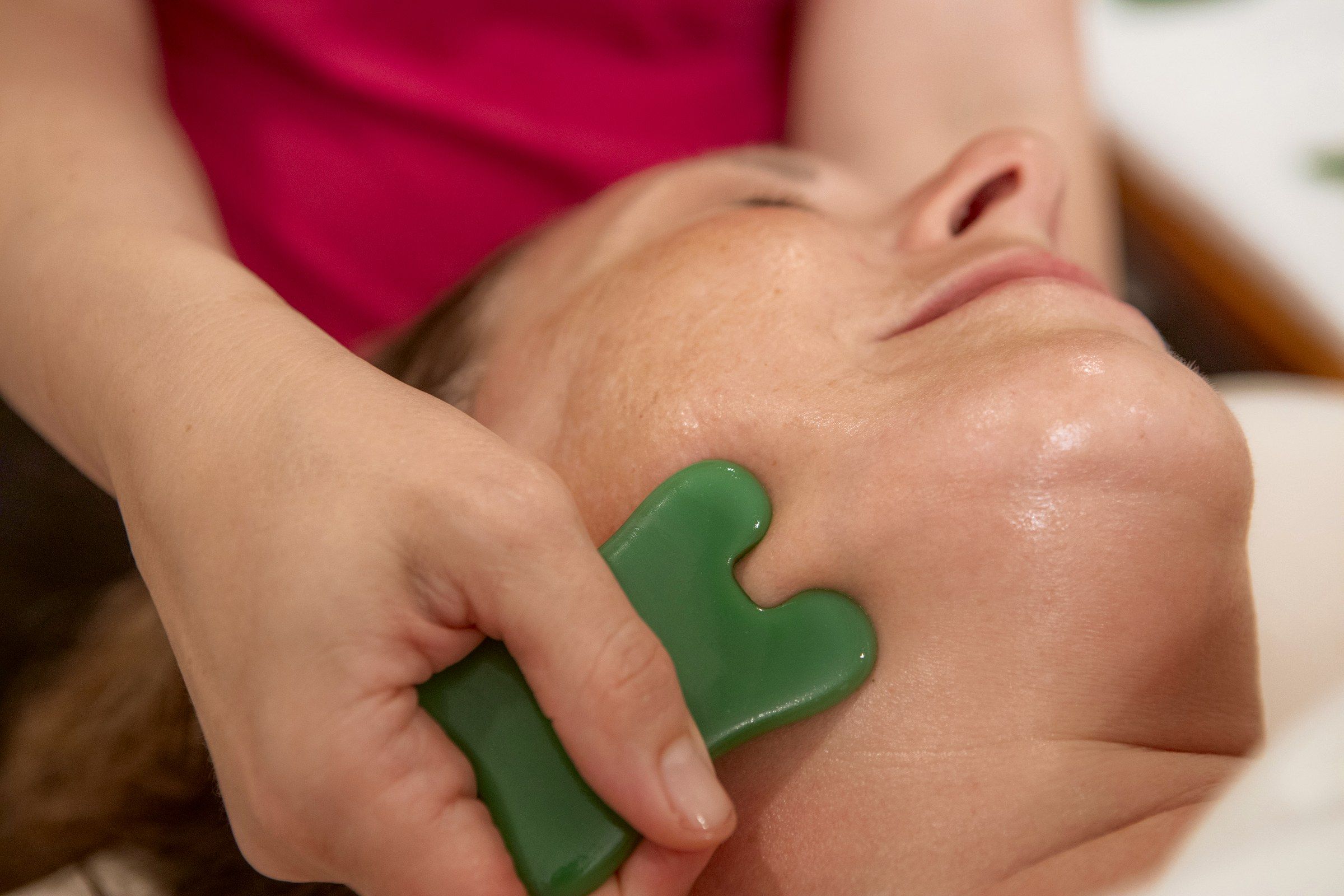 A gua sha stone on a client's cheek