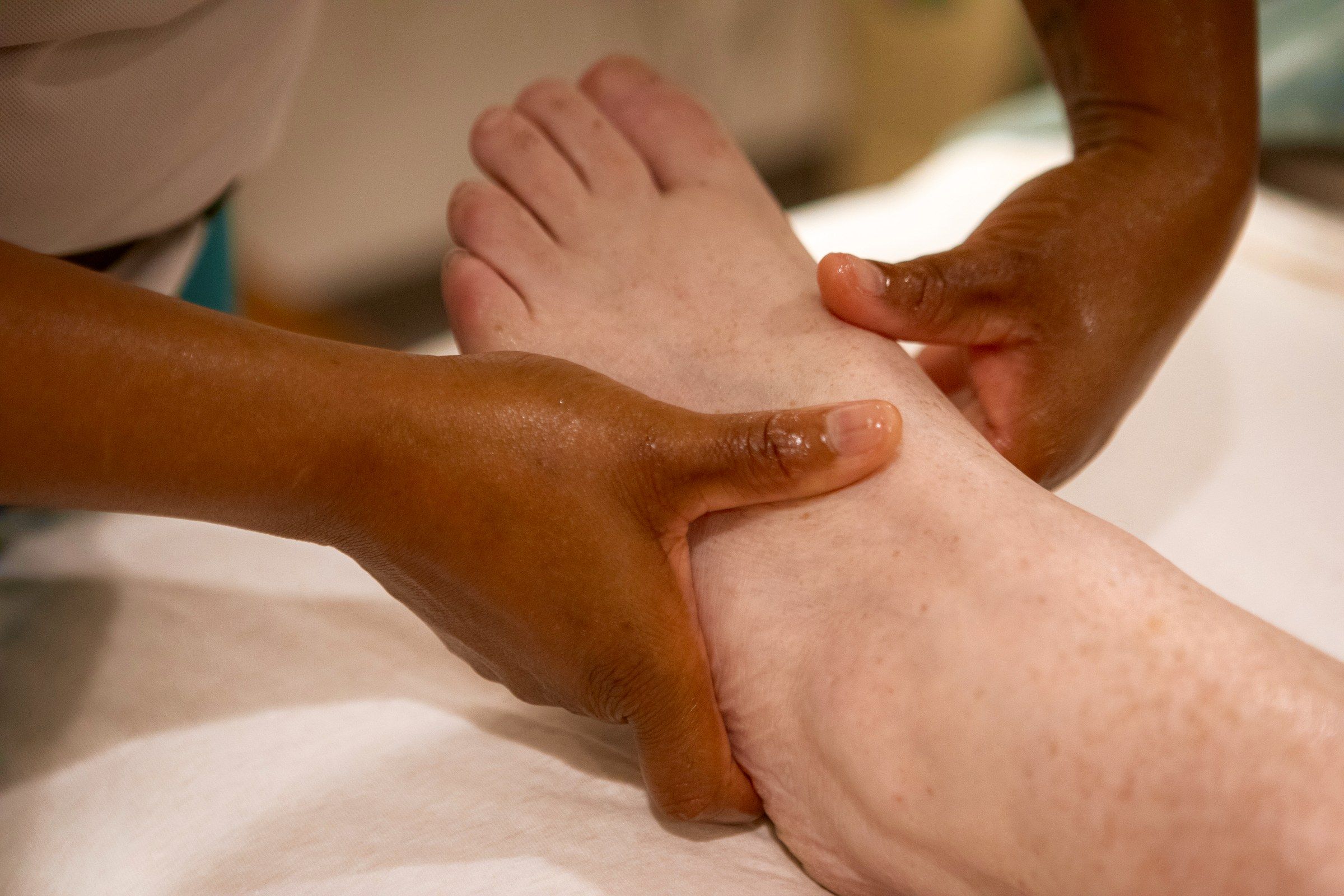 Alecia's hands working a client's foot and ankle