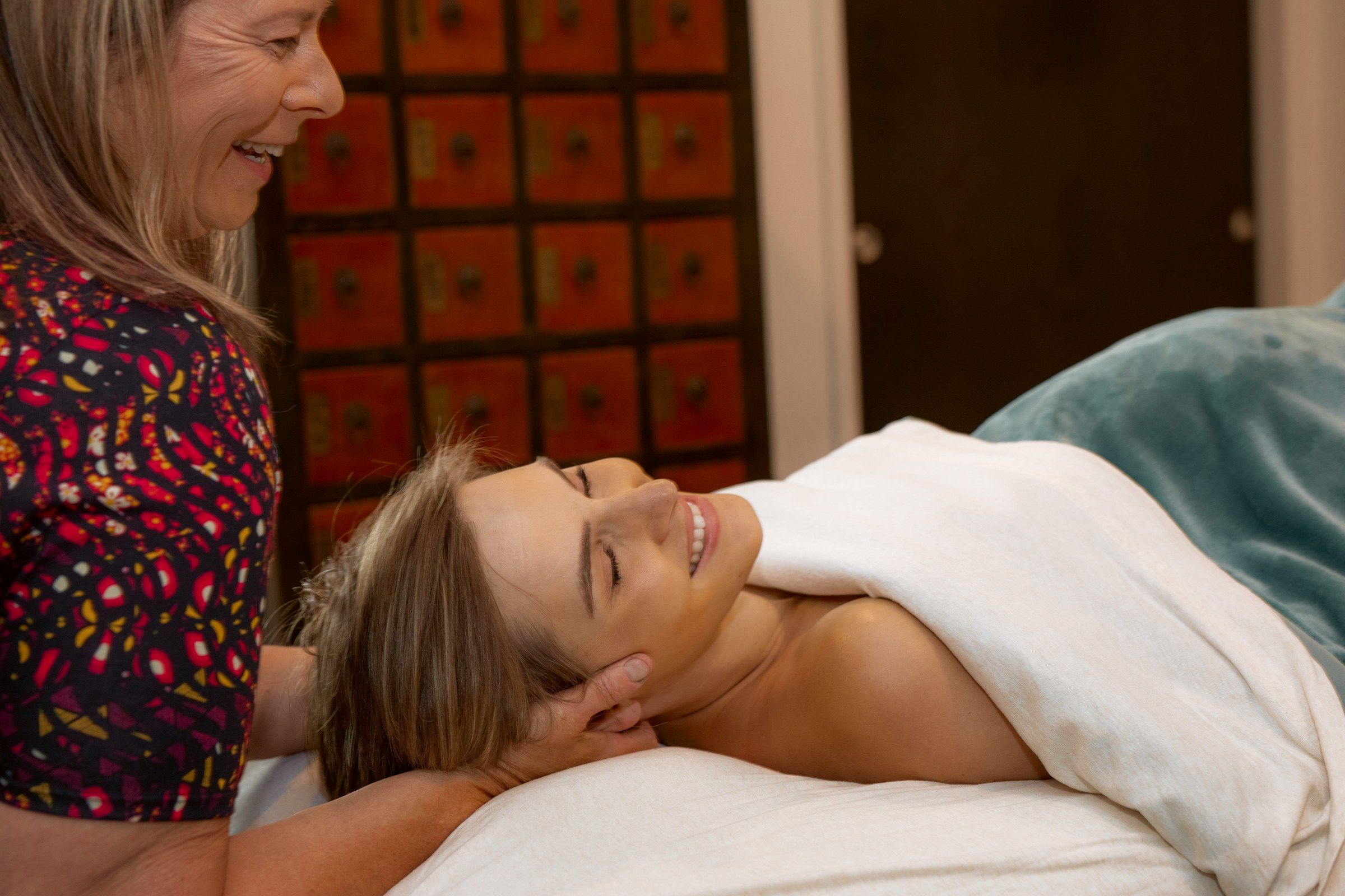 The therapist smiling as she works a client's neck during prenatal massage
