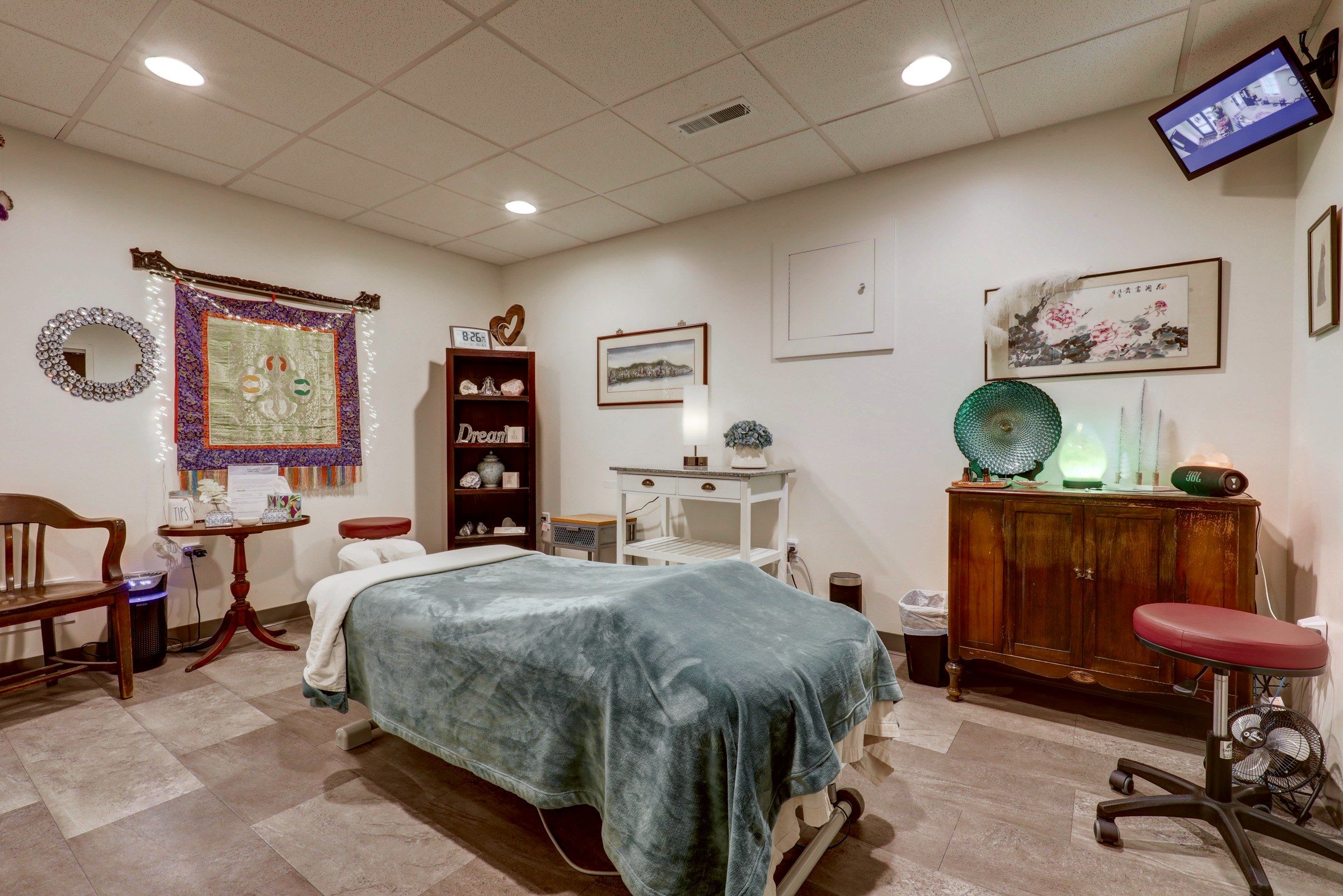 Treatment room with an embroidered wall hanging and a massage table