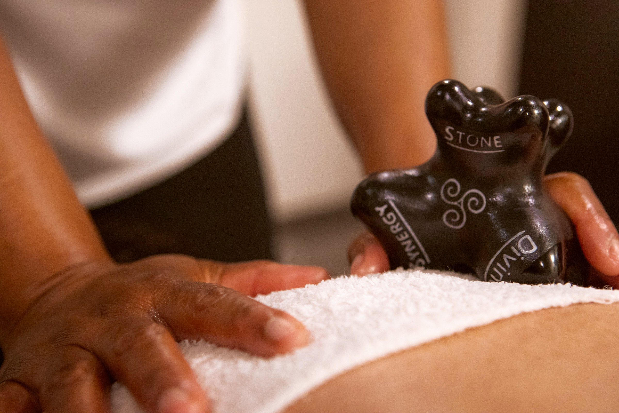 A Synergy stone on a towel across a client's back